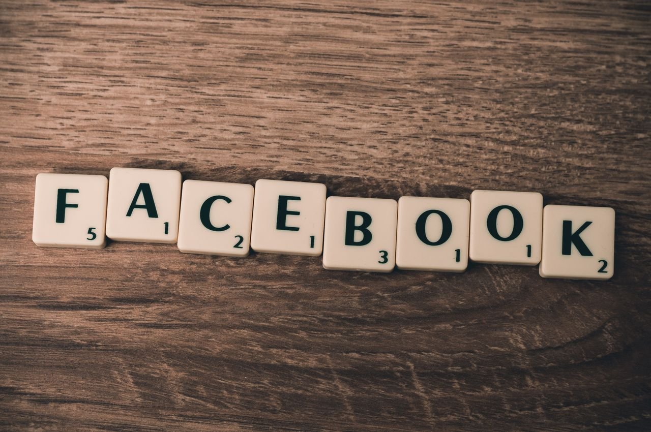 Home Scrabble tiles spelling 'Facebook' on a wood background, symbolizing social media.