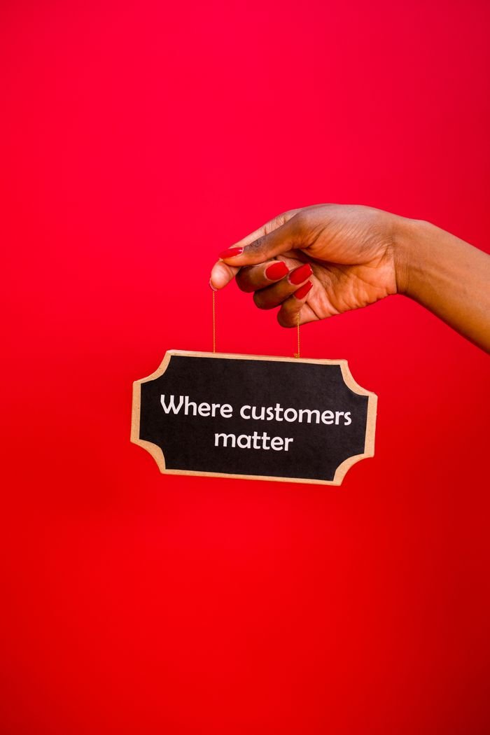 Home A hand holding a sign with the text 'Where customers matter' against a red background.